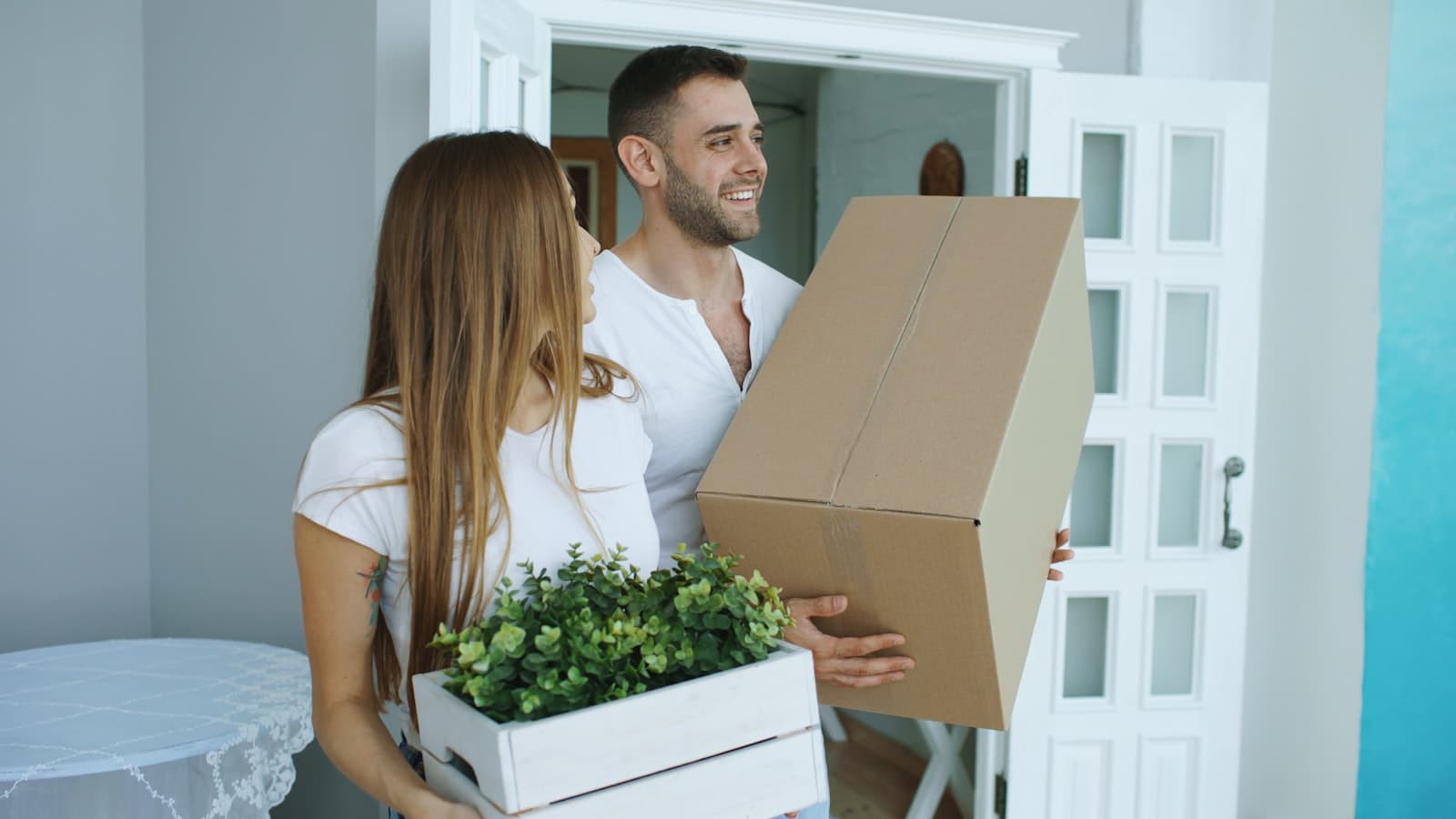 Stel draagt verhuisdozen een nieuwe woning binnen