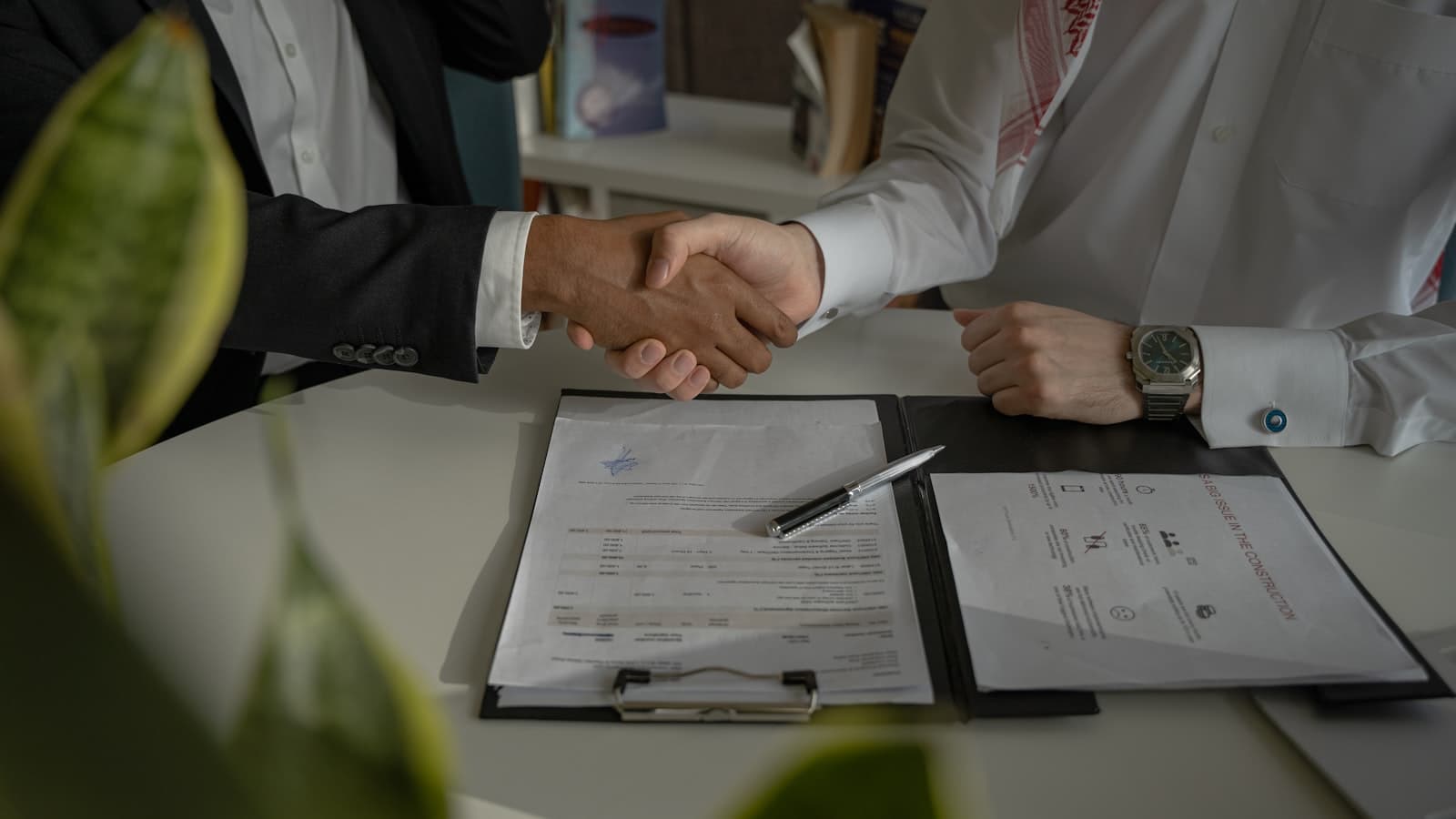Twee mensen schudden handen over een contract